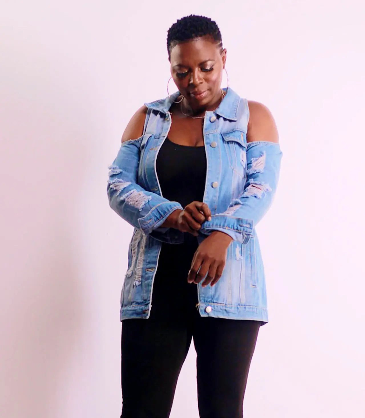 Close-up of the ripped long sleeve and shoulder cutout on the denim jacket.