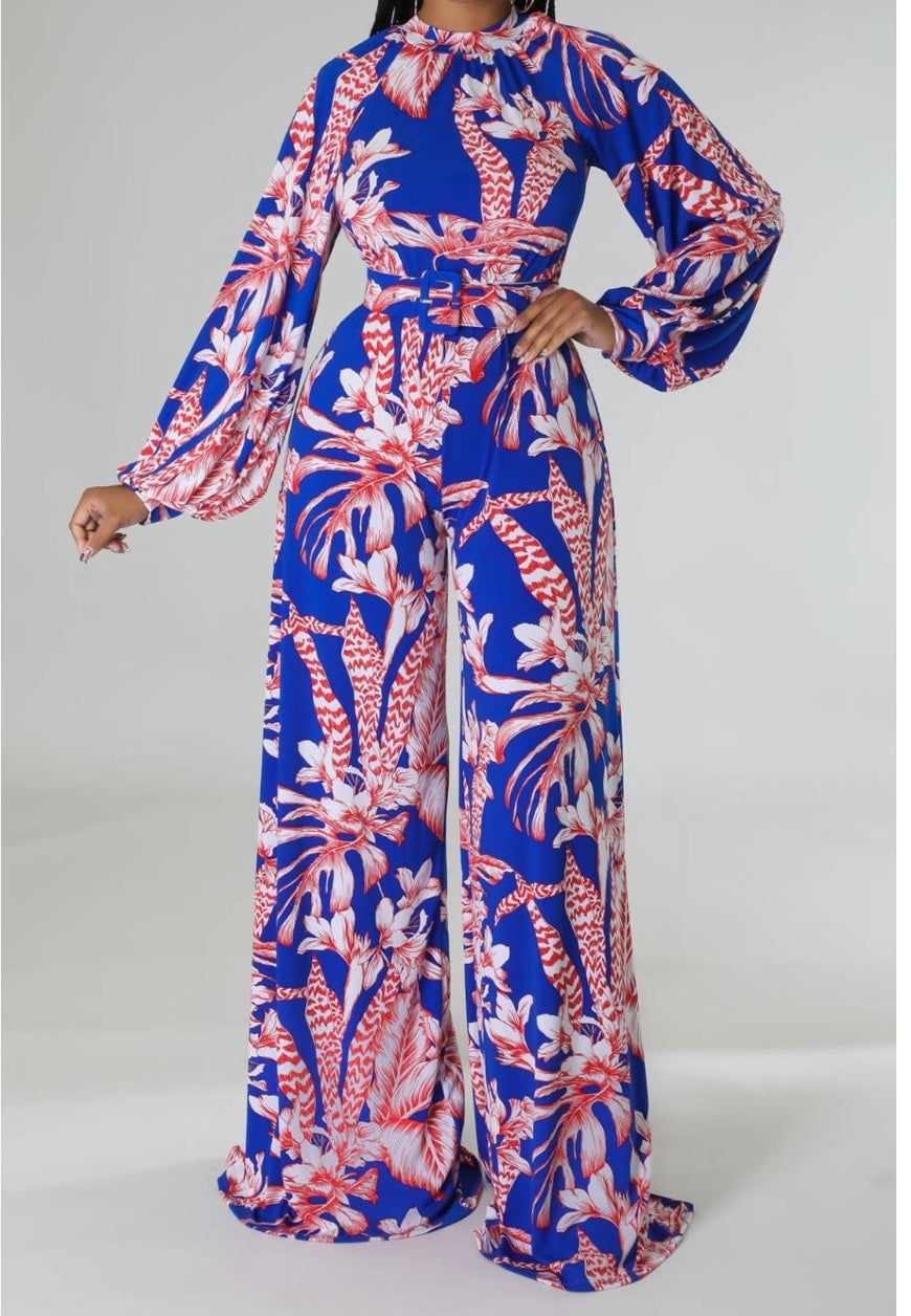 Model wearing a floral jumpsuit with long sleeves and wide legs in vibrant blue.