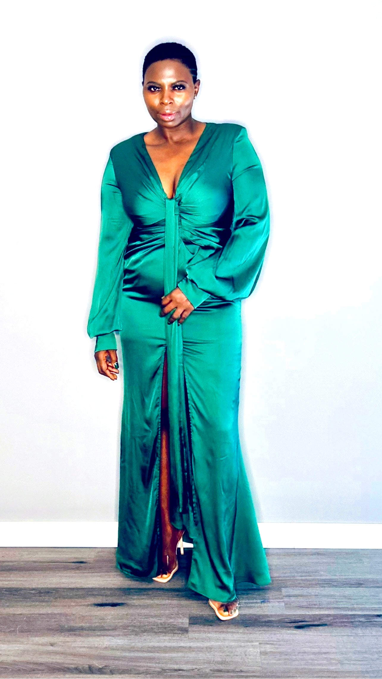 Model wearing a long sleeve emerald green satin maxi dress with a twist-front design