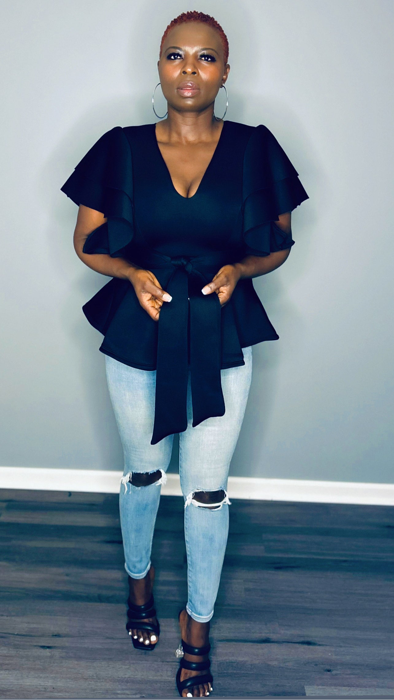 Full-length shot of the black v-neck flowy top styled with high-waisted jeans.